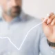 Pessoa desenha gráfico de crescimento para representar investimentos seguros
